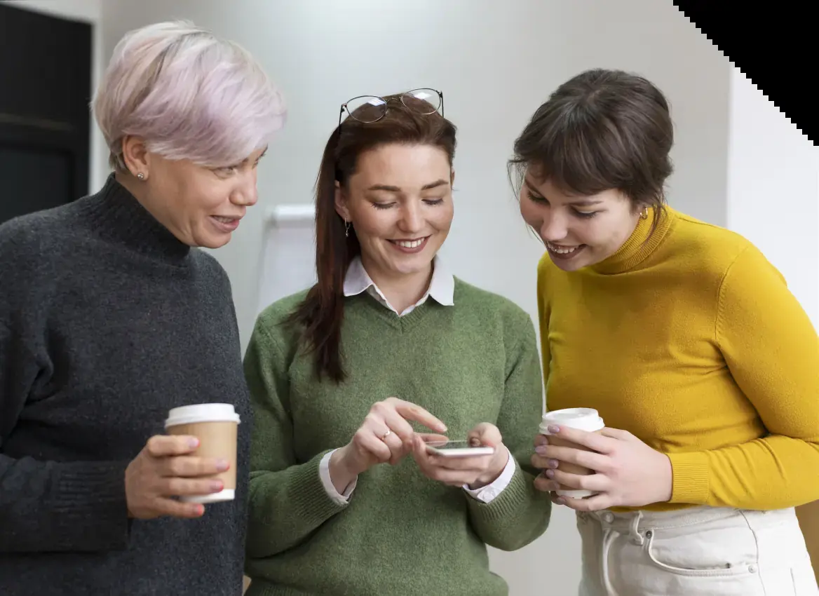 Drei Frauen betrachten gemeinsam ein Smartphone