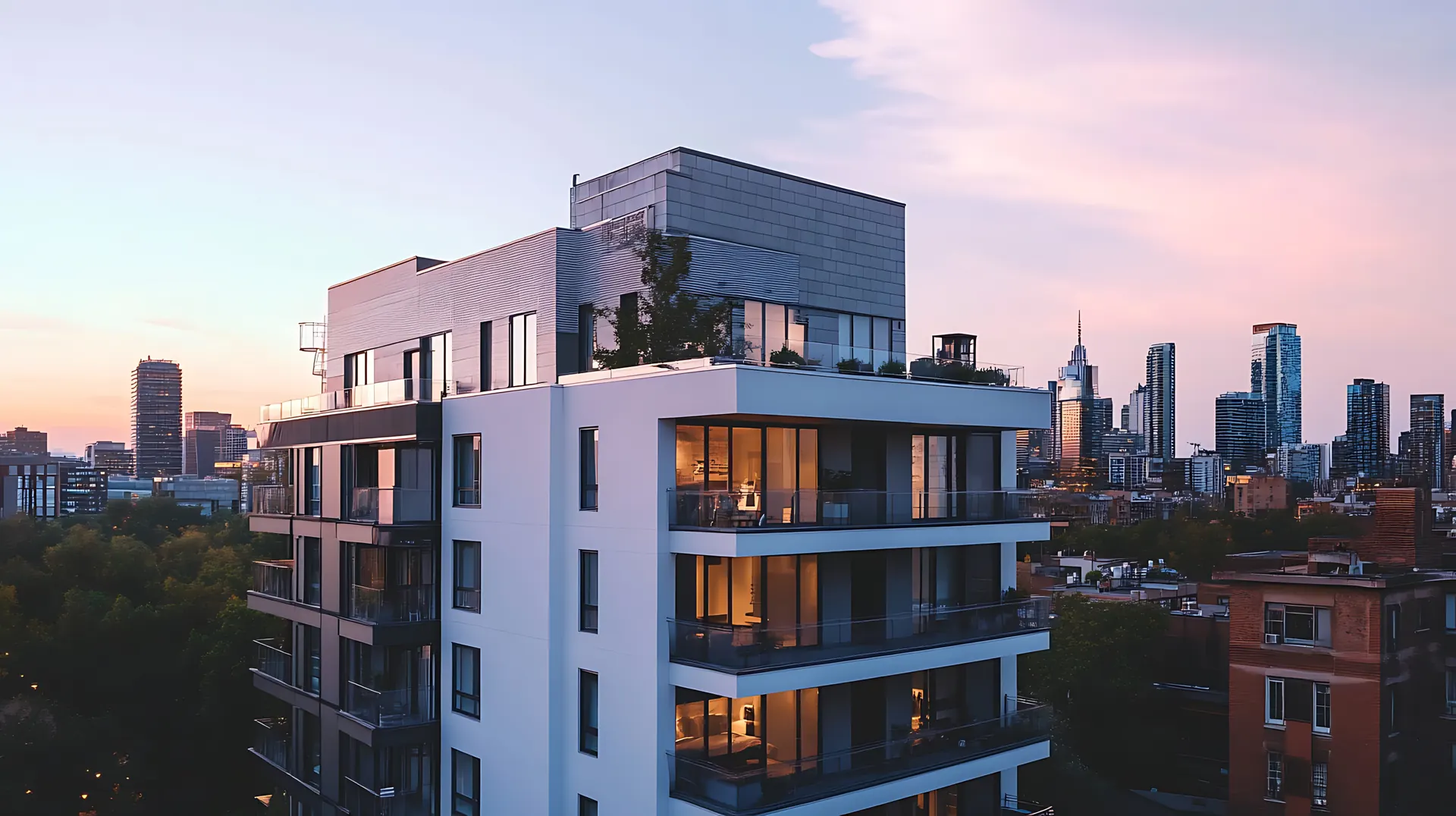 Modernes Apartmentgebäude bei Sonnenuntergang vor einer Stadtsilhouette